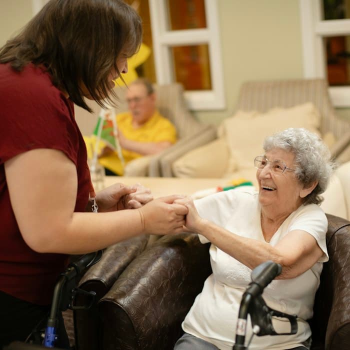 A caregiver holding hands with a smiling elderly woman