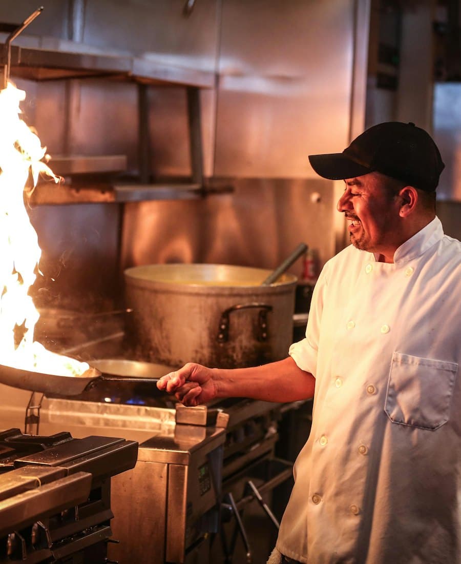 A chef cooking over a flame in a restaurant kitchen